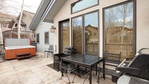 A patio with a grill, outdoor seating, and a hot tub.