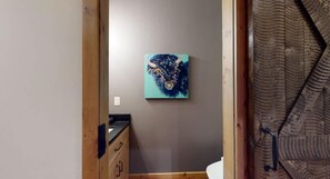 Un baño con un armario de madera, un lavabo y un cuadro colgado en la pared.