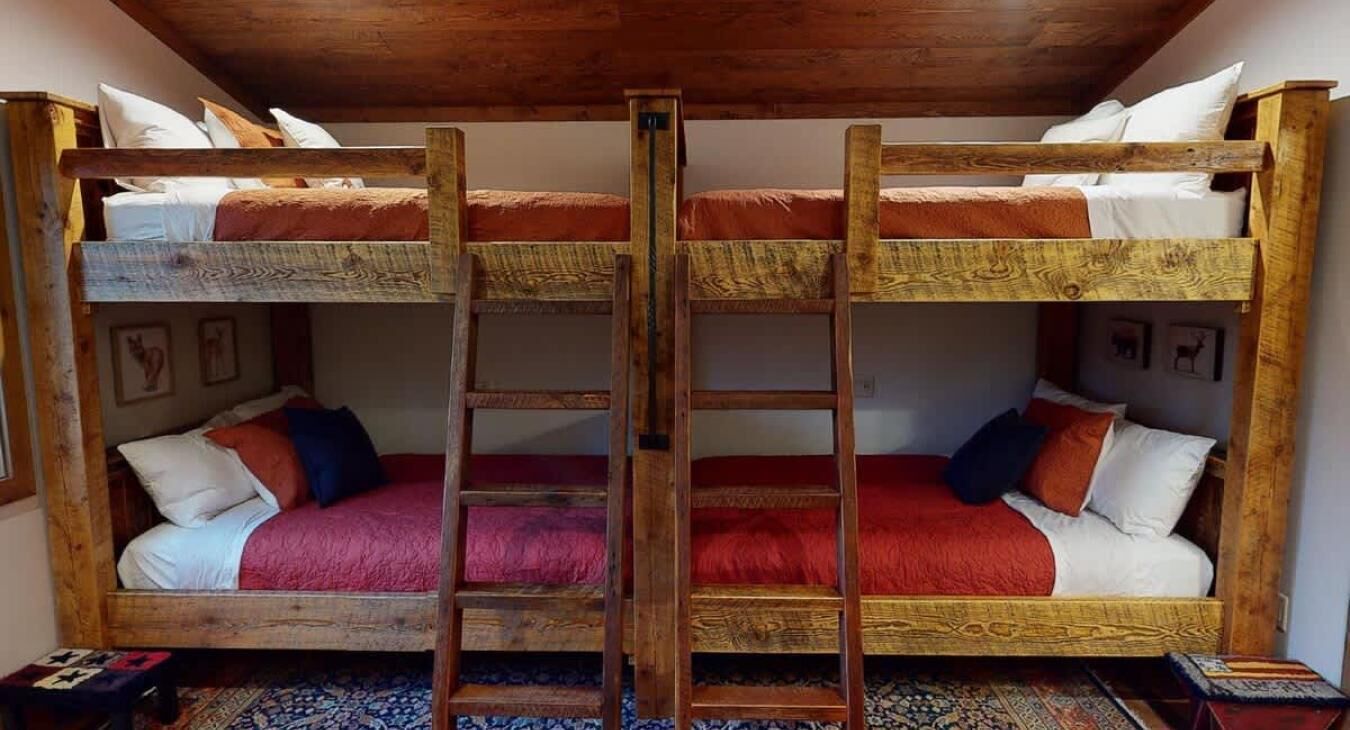 Habitació amb dos llits superposats, una escala i una catifa amb dibuixos.