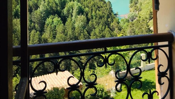 Ein Balkon mit Metallgeländer mit Blick auf eine Berglandschaft und einen See.