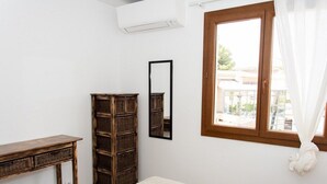 Una camera da letto con un letto, una cassettiera in legno, uno specchio e una finestra con tende.