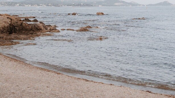 Una spiaggia con costa rocciosa e acqua calma.