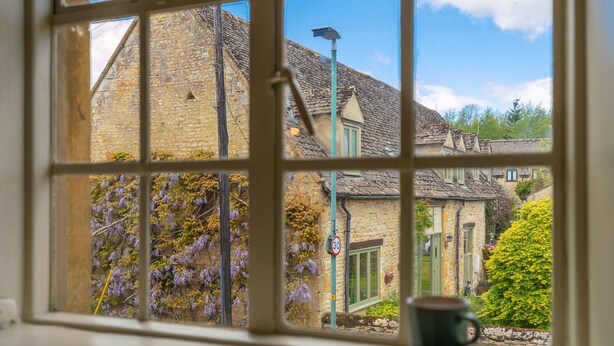 A view through a window with a stone building, a street lamp, and a speed limit sign. - Poppy Cottage - sleeps 4 guests  in 2 bedrooms (Broadwell)