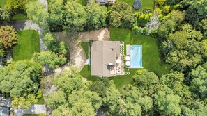 An aerial view of a residential property with a swimming pool, a patio area, and surrounding lush greenery. - Modern Coastal Farmhouse style home with a private pool, open-floor plan,... (Sag Harbor)