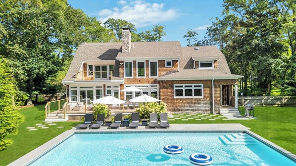 A two-story house with a swimming pool, outdoor seating, and a well-maintained lawn. - Modern Coastal Farmhouse style home with a private pool, open-floor plan,... (Sag Harbor)