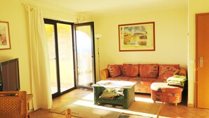 A living room with a sofa, a coffee table, a television, and a sliding glass door leading to an outdoor area. - lovely apartment with private swimmingpool and stunning views (Rosas / Roses)