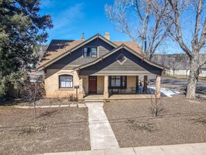 A two-story house with a front porch, a chimney, and a small front yard.