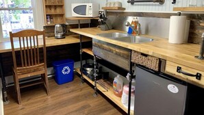 Una cocina compacta con encimera de madera, pileta integrada, microondas y refrigerador pequeño.