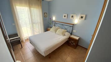 Een slaapkamer met een bed, nachtkastjes, een stoel en een raam met gordijnen.