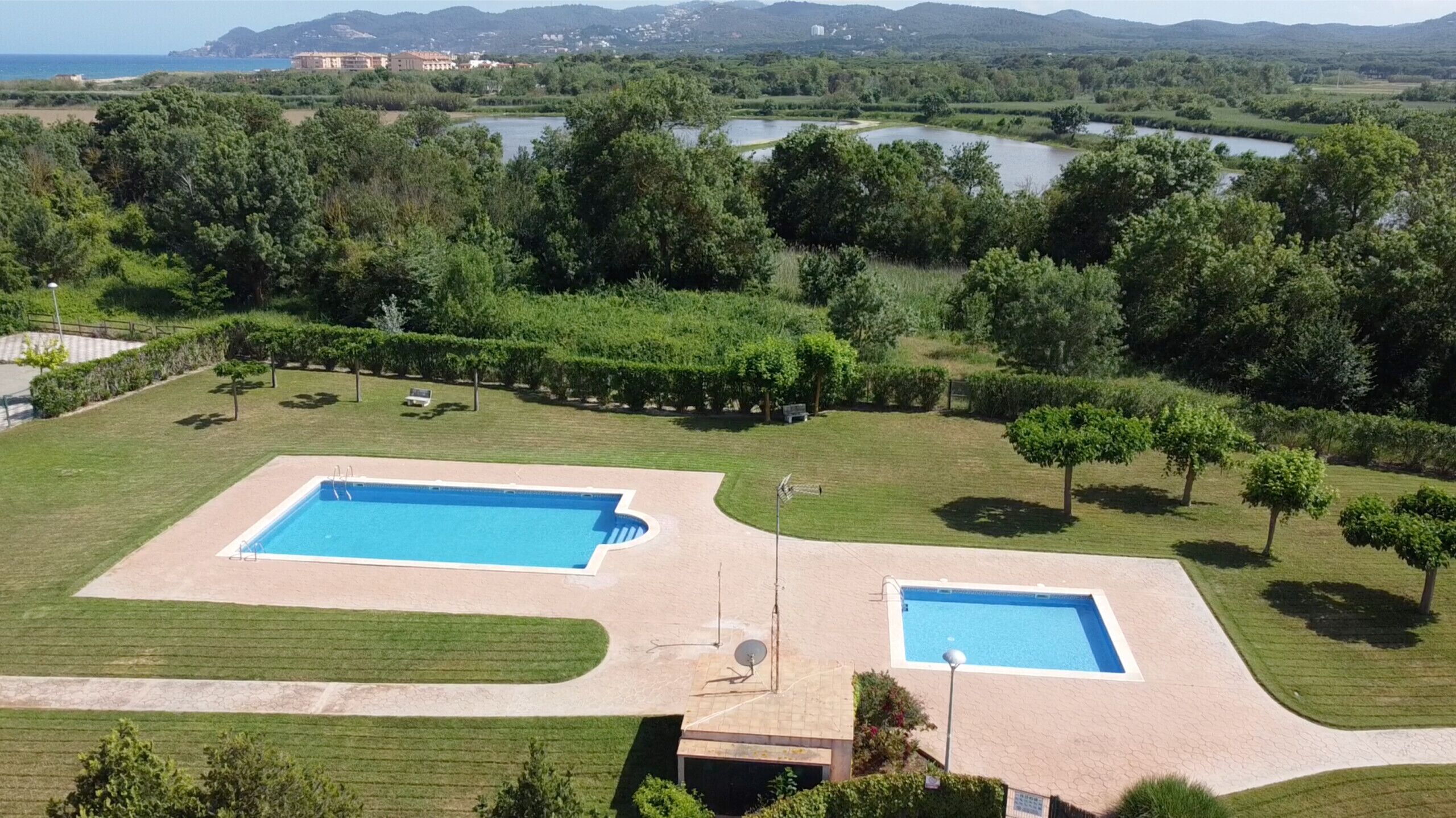 Una gran piscina al aire libre con césped y árboles alrededor.