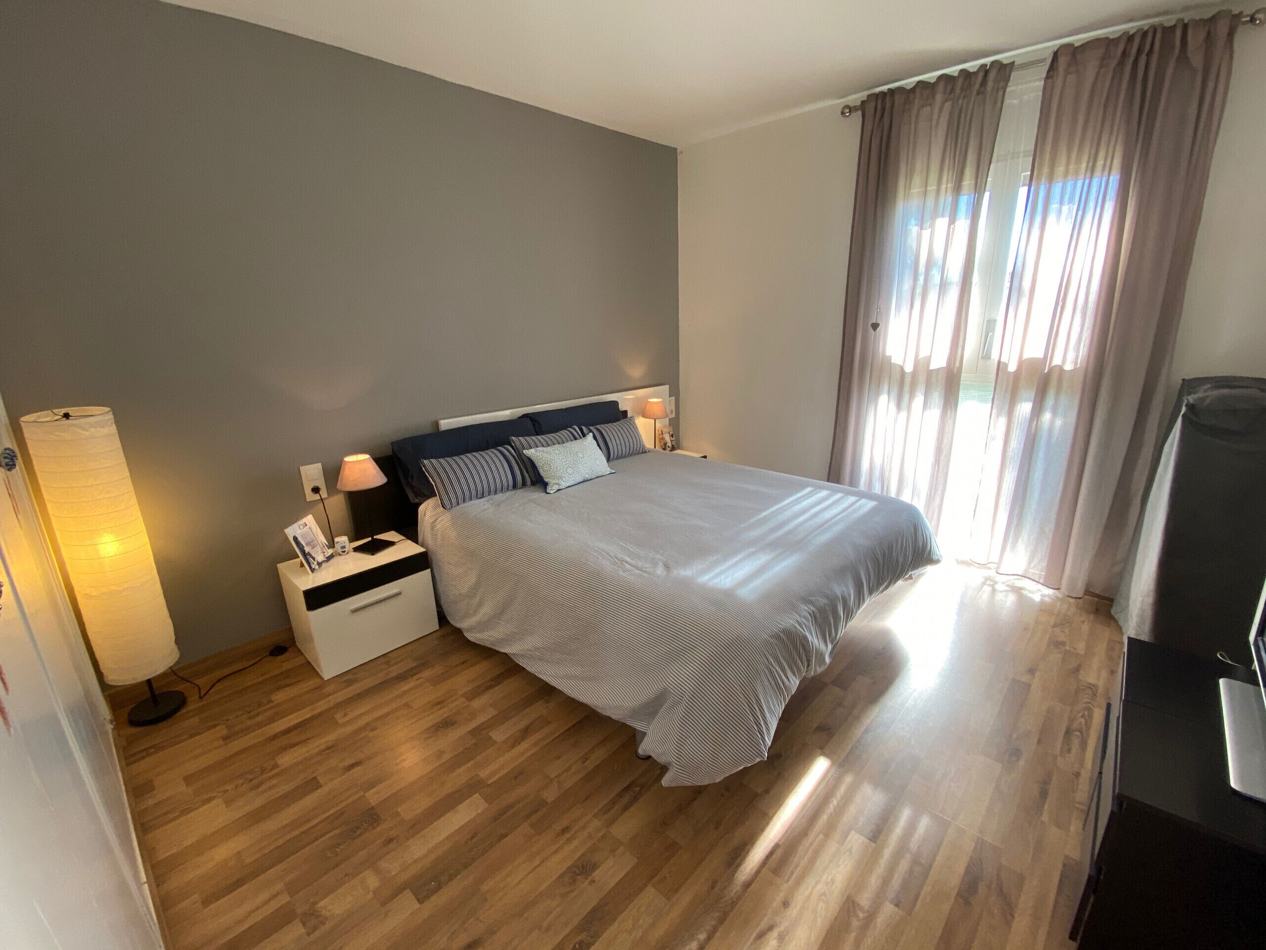 Une chambre à coucher bien rangée, avec un lit, des tables de chevet, une lampe et une chaise.
