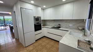 A modern kitchen with white cabinets, a built-in oven, and a refrigerator. - Daró 3D 49 - Aircon, pool, corner house, 250m from the beach (Torroella de Montgri)