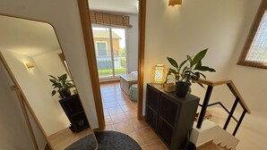 A staircase with a dark carpet, a wooden handrail, a potted plant, and a wall-mounted lamp. - Daró 3D 49 - Aircon, pool, corner house, 250m from the beach (Torroella de Montgri)