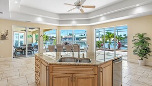Una cocina moderna con una isla central, ventanas amplias y vista a una piscina.