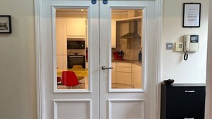 Puertas dobles con un panel de vidrio, un certificado enmarcado en la pared y un teléfono a la derecha.