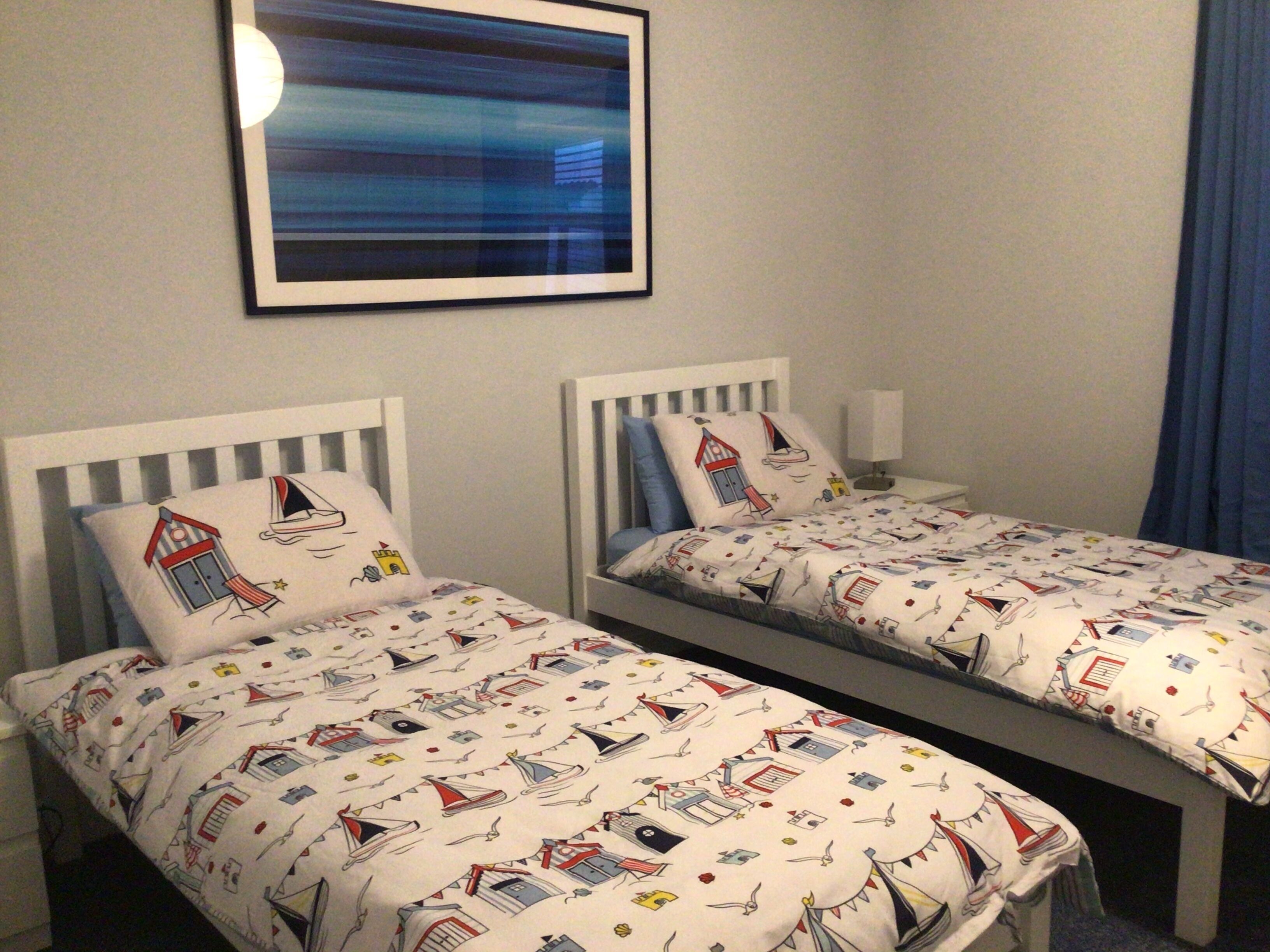 Two single beds with matching headboards and footboards, each with a pillow and a bedside table.