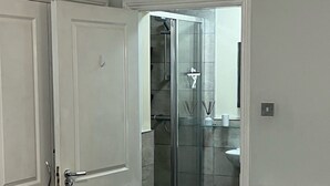 Un dormitorio con cama, una puerta y un baño con ducha e inodoro.
