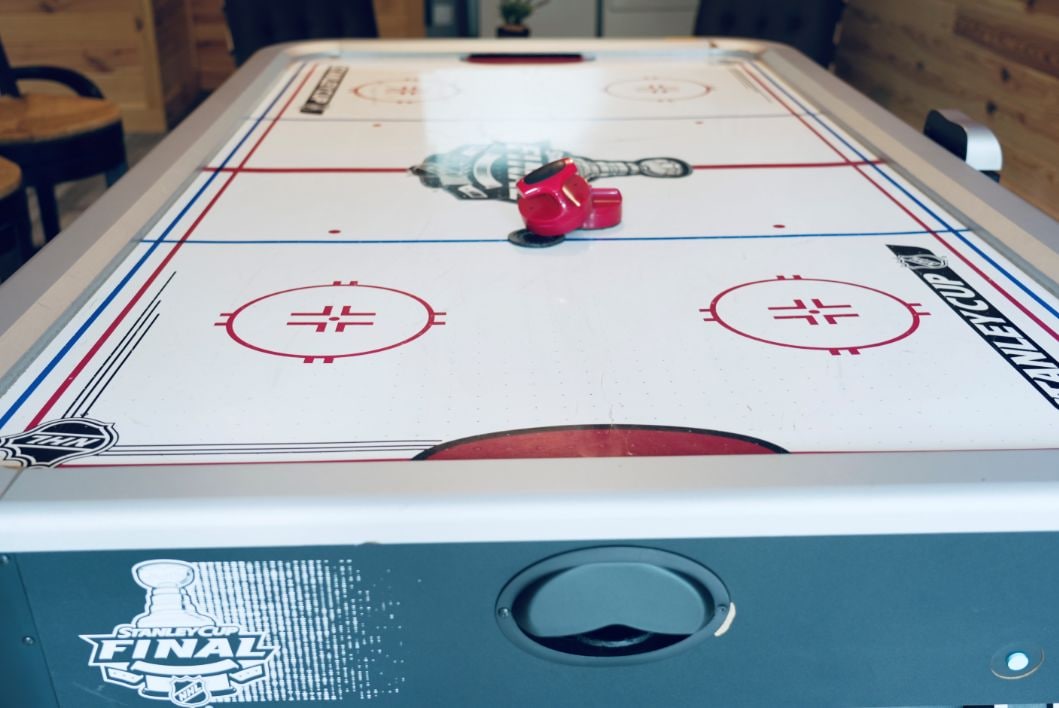 A table hockey game with a puck and a red cup on the table.