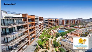 Un hôtel à plusieurs étages doté de balcons, d’une piscine et de jardins aménagés.