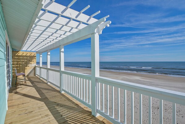 A wooden deck with a white railing overlooking a beach. - On the Ocean (North Topsail Beach)