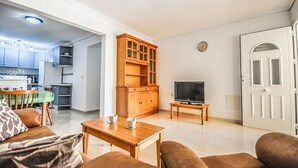 En kompakt bolig med tekøkken, spiseplads, TV og en dør.