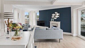 Ein modernes Wohnzimmer mit einem grauen Sofa, einem Esstisch mit Blumenvase und einem Kamin.