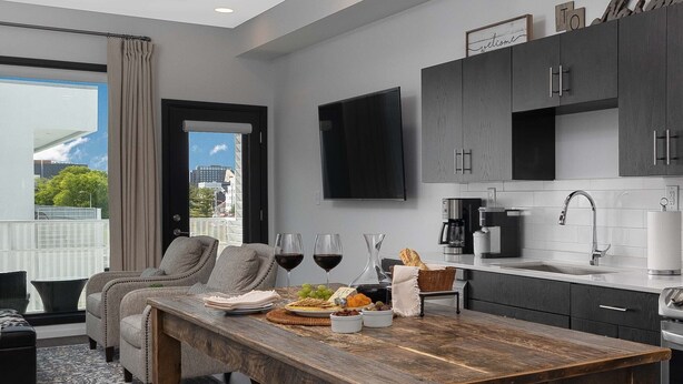 Una cocina moderna con armarios oscuros, una mesa de comedor de madera y vistas a la ciudad.