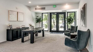 Un área de recepción moderna con mostrador, dos sillones, una mesita de centro y un ventanal con vistas a la calle.