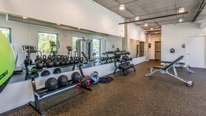 Un gimnasio con equipo de ejercicio, un espejo grande y una cinta de correr.