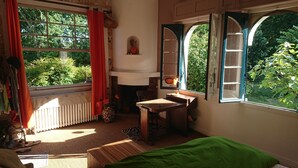 Een kamer met een groot raam, een houten bureau, een stoel, een radiator en een groene sprei.