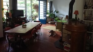 Een ruime woonkamer met een eettafel, stoelen, een bank en een hond.