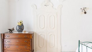 Una habitación con un aparador de madera, una puerta blanca con molduras decorativas y una estructura de cama metálica.