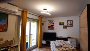 Een slaapkamer met een bed, een bureau, een stoel, een televisie en kunst aan de muren.