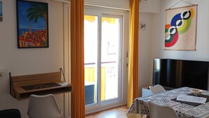 Een kamer met een houten bureau, een stoel, een televisie en een tafel met een kom en papieren.