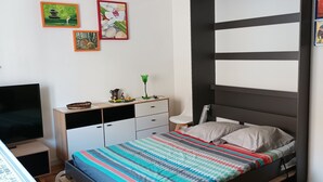 Een slaapkamer met een bed, televisie, bureau en een boekenkast.