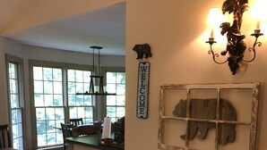 Ein gemütliches Wohnzimmer mit einem beigefarbenen Sofa, einem 'WELCOME'-Schild und rustikaler Wandgestaltung.