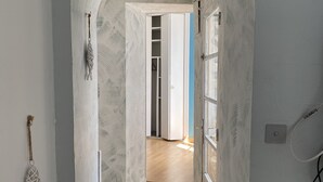 Een gang met een witte boog die leidt naar een kamer met een houten vloer en een deur.