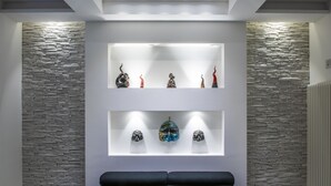 Una habitación moderna con pared de piedra y dos estantes iluminados que exhiben objetos decorativos.