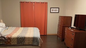 Una camera da letto con un letto, una cassettiera, un armadio e una ventola a soffitto.