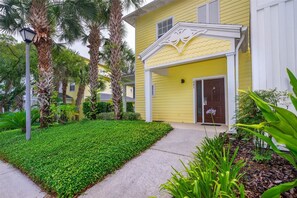 A yellow building with a white porch and a brown door.