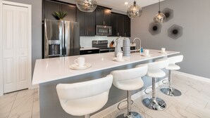 A modern kitchen with a large island, stainless steel appliances, and pendant lighting.