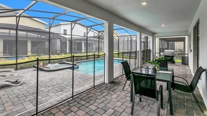 A covered patio with a pool, outdoor seating, and a grill area. - Elegant 9 BR Mansion Center of Attractions 4515 (Kissimmee)