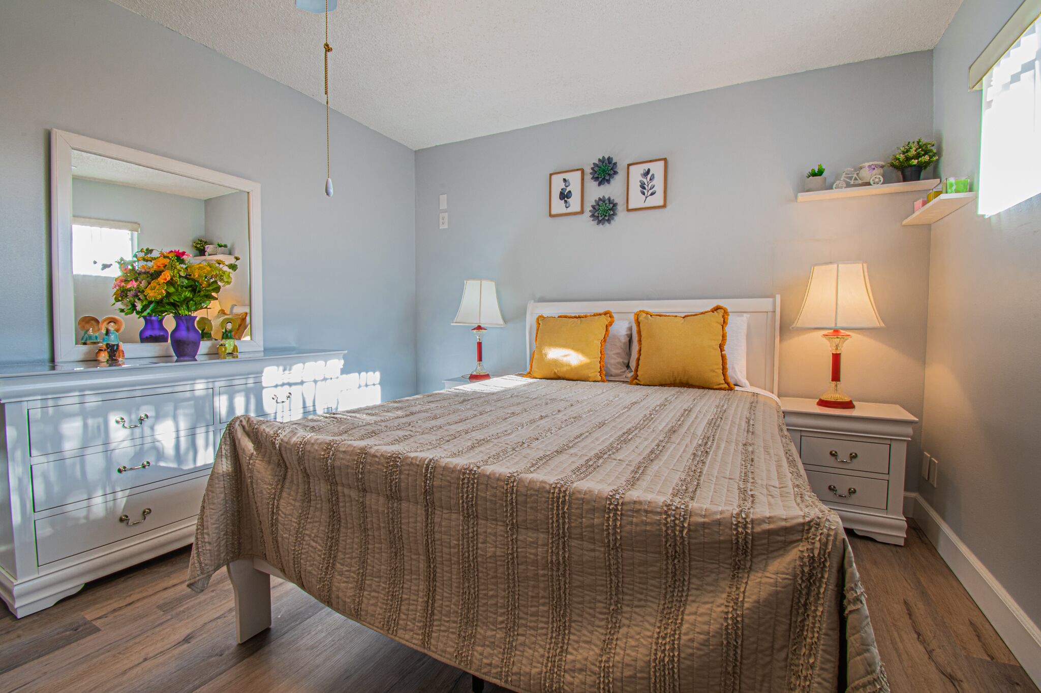 A bedroom with a bed, nightstands, a dresser, and a mirror.