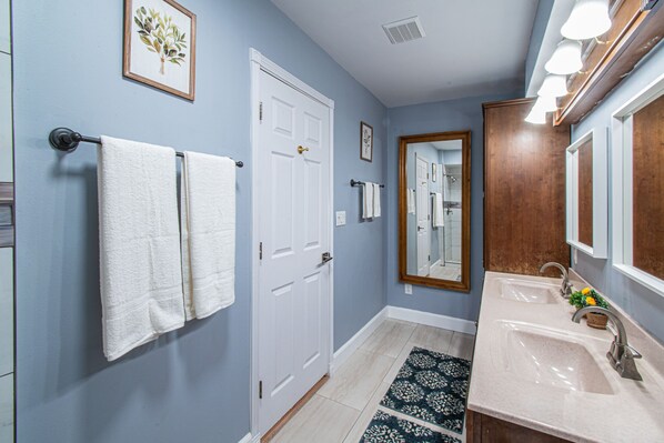 Une salle de bain avec un lavabo, un miroir, un porte-serviettes et une porte.