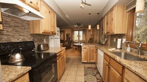 A modern kitchen with wooden cabinets, granite countertops, and a built-in oven. - Steps away from Wild Basin:RMNP- 2-bdrm cabin perfect for adventure or relaxing! (Allenspark)