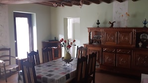 A dining area with a table set for four, surrounded by wooden chairs. A wooden cabinet with decorative items is against the wall. - Gîte à la Campagne "beauregard" à LA Fleche (La Flèche)
