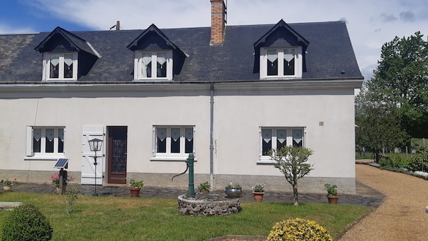 A two-story house with a white exterior, a dark roof, and multiple windows with white frames. - Gîte à la Campagne "beauregard" à LA Fleche (La Flèche)