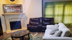 Uma sala de estar com lareira, sofá de couro e tapete estampado.