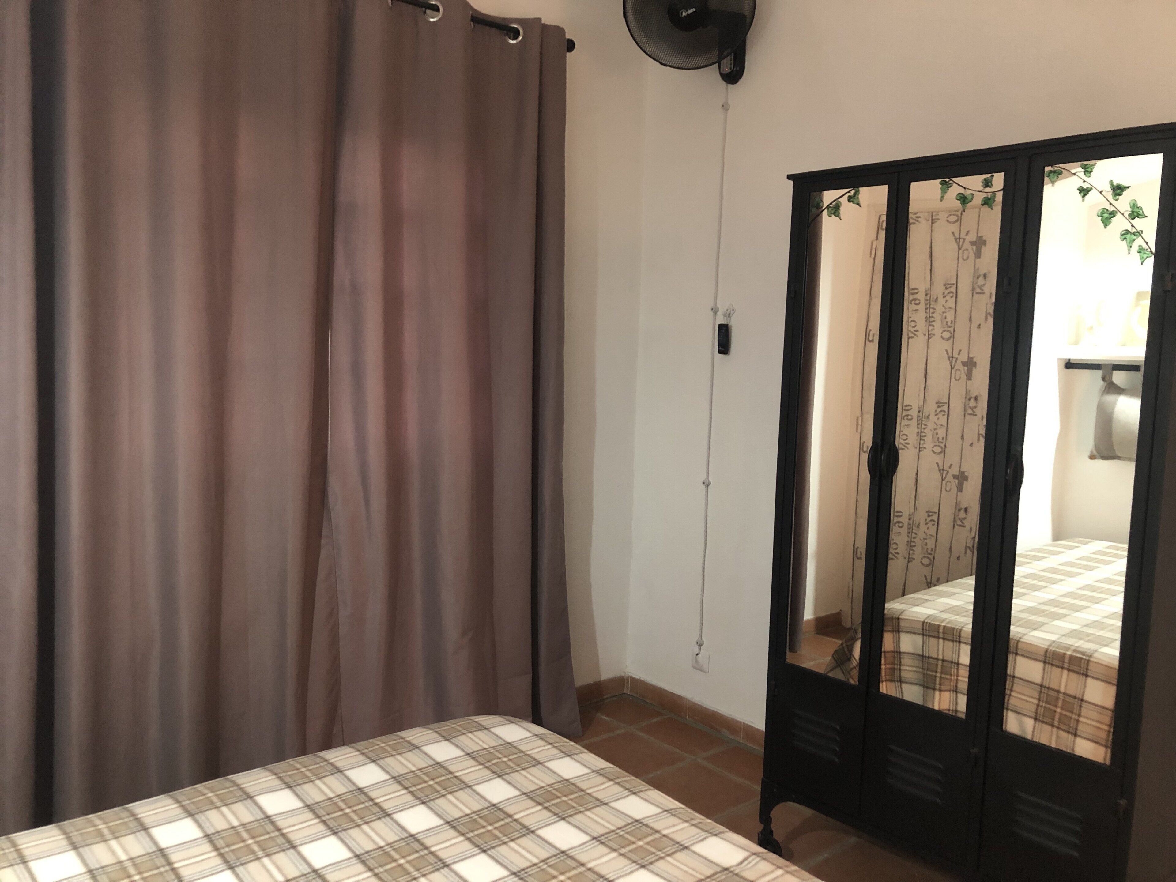Une chambre à coucher avec un lit, une armoire et un rideau.