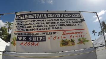 Un letrero anuncia artesanías y recuerdos de Kona Marie's Farm, incluyendo café cultivado en Hawái y joyería tropical hecha a mano.